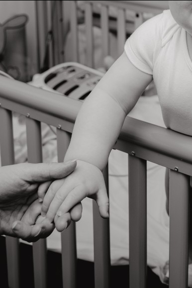 black and white image of adult hand holding a baby's hand